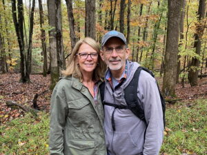 George standing with his wife in the woods